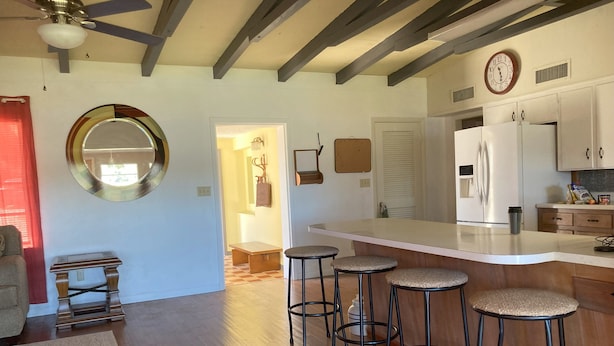 A modern kitchen with a white countertop, bar stools, and a clock on the wall.