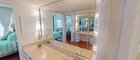 A bathroom with a large mirror, a sink, and a toilet.