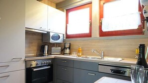 Ett kompakt kök med mikrovågsugn, brödrost, kaffebryggare och en diskho.
