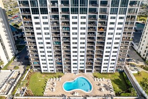 A high-rise building with multiple balconies, a swimming pool, and a parking area. - Emerald Towers 904 2 Bedroom Condo (Destin)