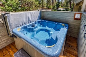 Un jacuzzi en una terraza de madera con vista a árboles.