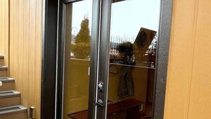 A sliding glass door with a black frame, leading to a room with a wooden interior and a visible staircase. - Downtown Sequim Penthouse, Elegant Decor (Sequim)