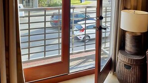 A room with a sliding glass door leading to an outdoor area with a view of a parking lot and a building. - Downtown Sequim Penthouse, Elegant Decor (Sequim)