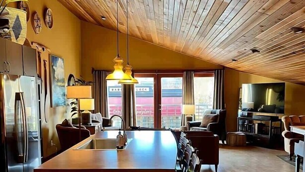A spacious kitchen with a wooden ceiling, a central island, and a large window. - Downtown Sequim Penthouse, Elegant Decor (Sequim)