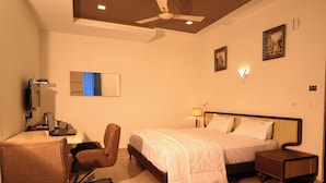 Une chambre d’hôtel équipée d’un lit, d’un bureau, d’une chaise et d’un ventilateur de plafond.