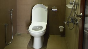 Une petite salle de bain compacte, équipée de toilettes, d’une douche et d’un lavabo.