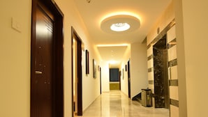 Un couloir bien éclairé, doté d’un sol en marbre, avec une porte sur la gauche et un luminaire fixé au mur.