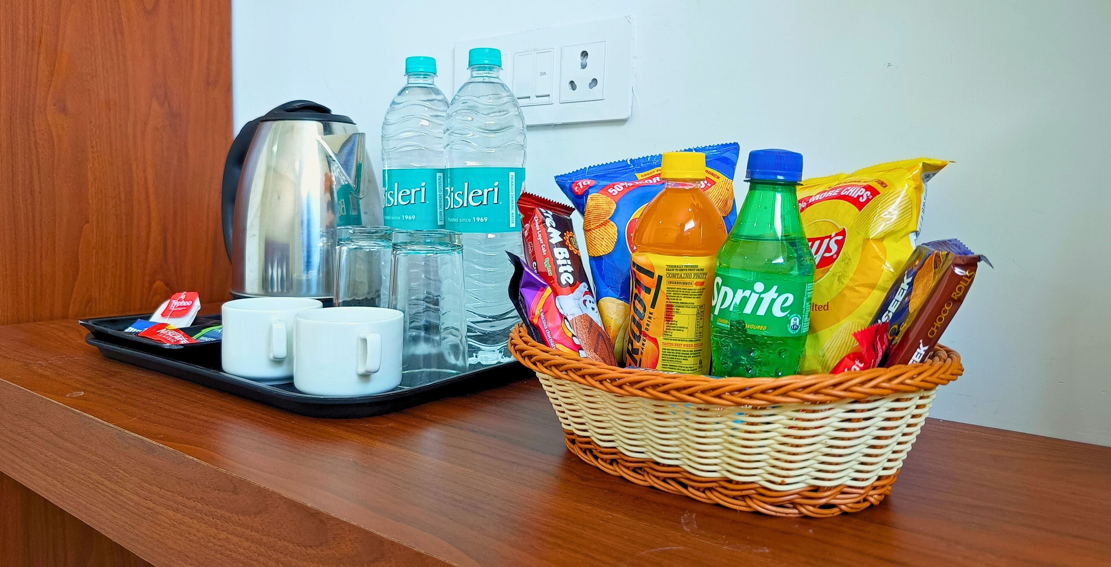 A tray with water bottles, a kettle, and white mugs on a wooden table.