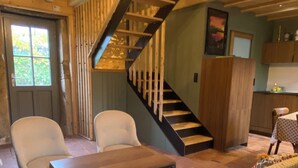A cozy living room with a sofa, chairs, a coffee table, a staircase, and a kitchen area.