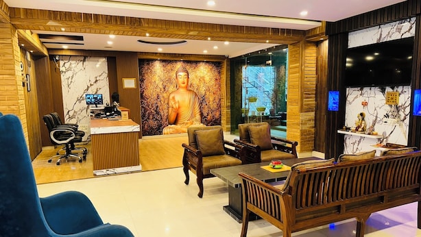 A modern interior with a reception desk, seating area, and a Buddha statue.