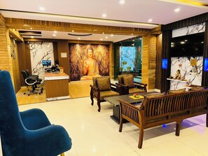 A modern interior with a reception desk, seating area, and a Buddha statue.