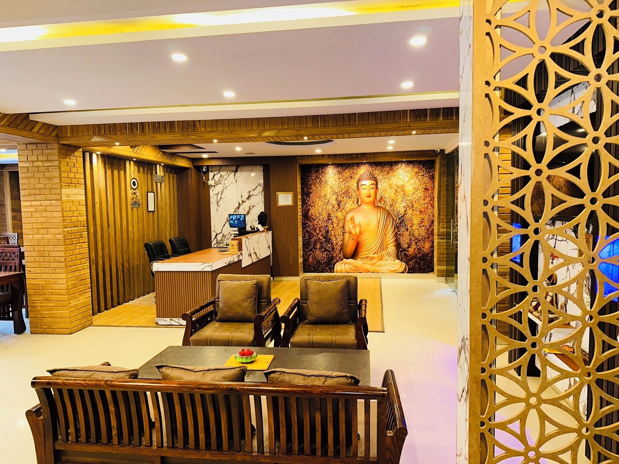 A reception area with a receptionist desk, seating, and a Buddha statue.