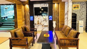 A modern living room with wooden furniture, a marble accent wall, and a TV.