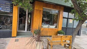 A wooden exterior with a large window, a bench, and a potted plant. - Hotel Vida (Puerto Madryn)