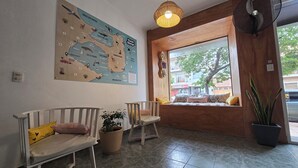A cozy seating area with two chairs and a table, a large map on the wall, and a window with a view of the street. - Hotel Vida (Puerto Madryn)