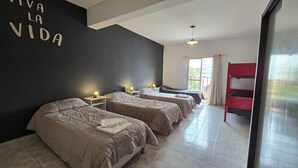 A hotel room with two beds, a black wall with 'VIVA LA VIDA' written on it, a red bunk bed, and a window with curtains. - Hotel Vida (Puerto Madryn)