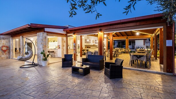 Area patio esterna con pavimento in pietra, mobili in vimini e una poltrona amaca.