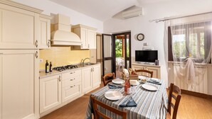 Una cucina moderna con mobili bianchi, un tavolo da pranzo apparecchiato per quattro persone e una TV nell'angolo.