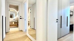 A modern hallway with a wooden floor, white walls, and a large mirror. - Apartments Onia Budva (Budva)