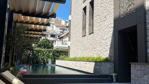 A modern outdoor pool area with lounge chairs, a stone building, and a clear view of the surrounding neighborhood. - Apartments Onia Budva (Budva)