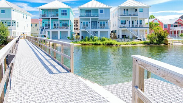 A waterfront property with multiple multi-story buildings, a wooden dock, and a calm river.
