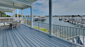 A covered deck with a view of a marina and houses in the distance.