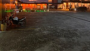 A hotel with a prominent neon sign, paved courtyard, and a mountain backdrop. - ABE HOTEL & CONVENTION (Siborongborong)