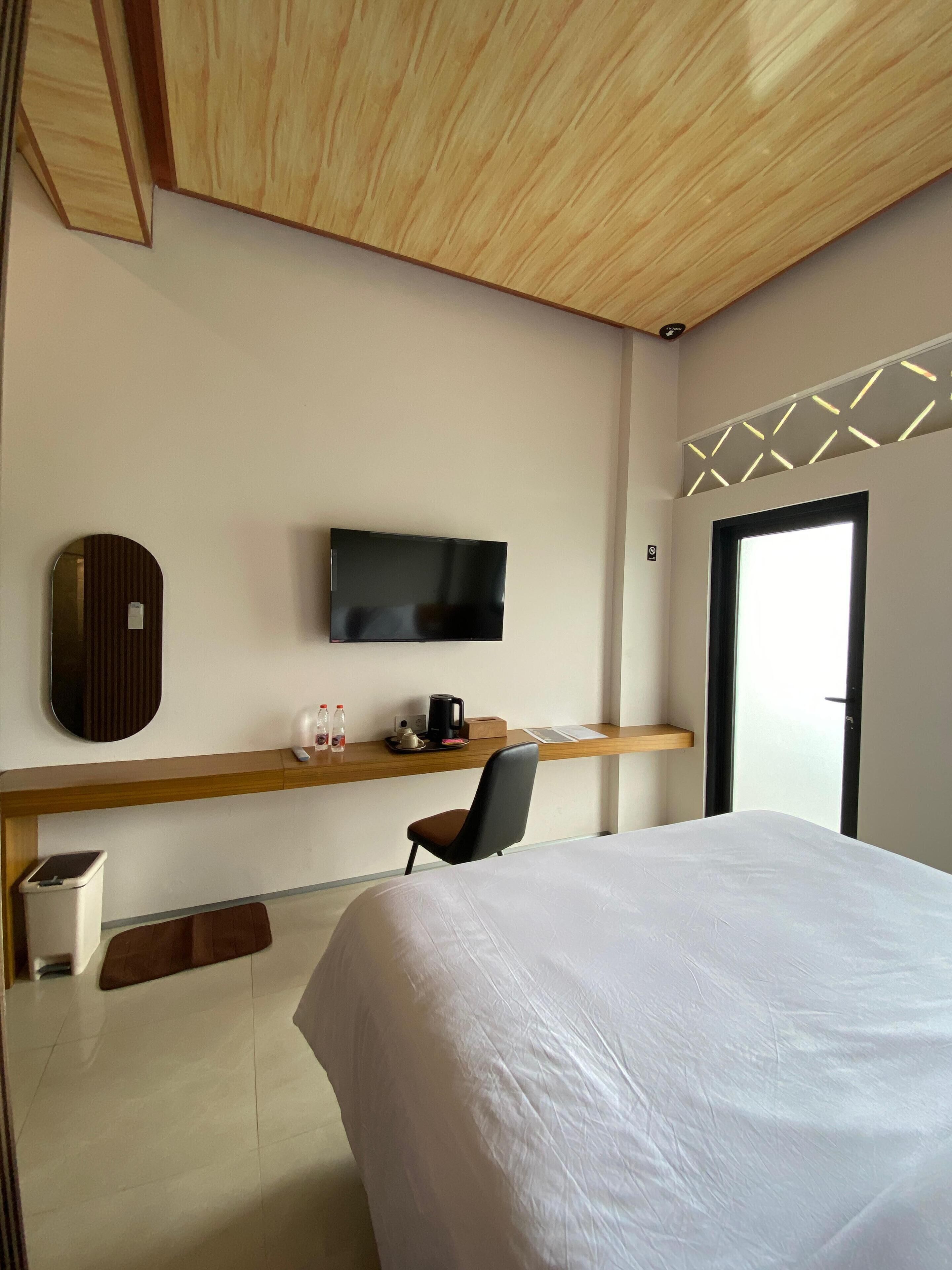 Una habitación de hotel con cama, escritorio con televisor, silla y ventana con vistas.