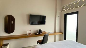 Una habitación de hotel con cama, escritorio con televisor, silla y ventana con vistas.
