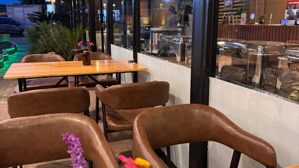 A restaurant with wooden tables and chairs, a view of the street, and a sign for Tong's Coffee. - ABE HOTEL & CONVENTION (Siborongborong)