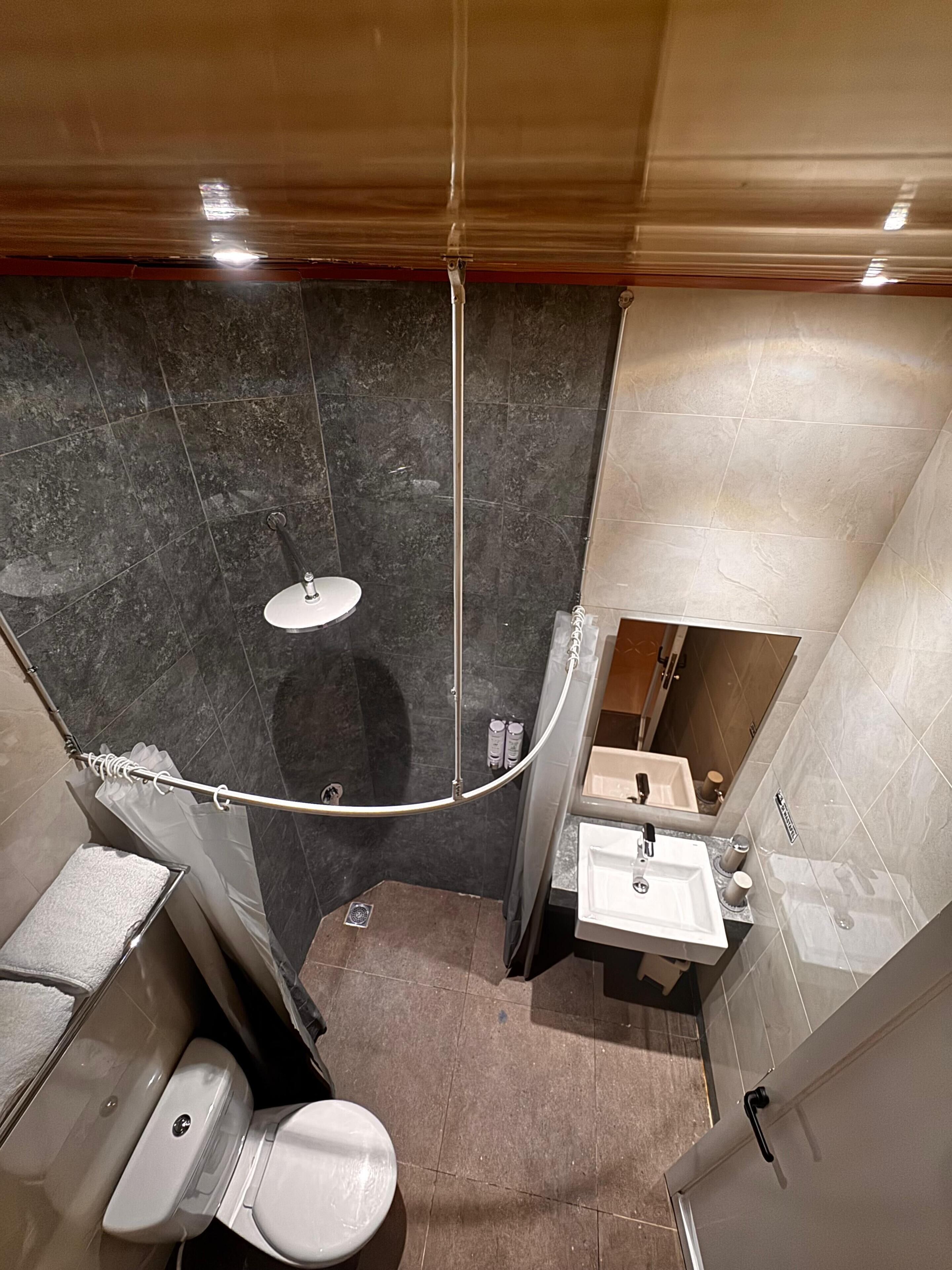 A compact bathroom with a shower, toilet, and sink.