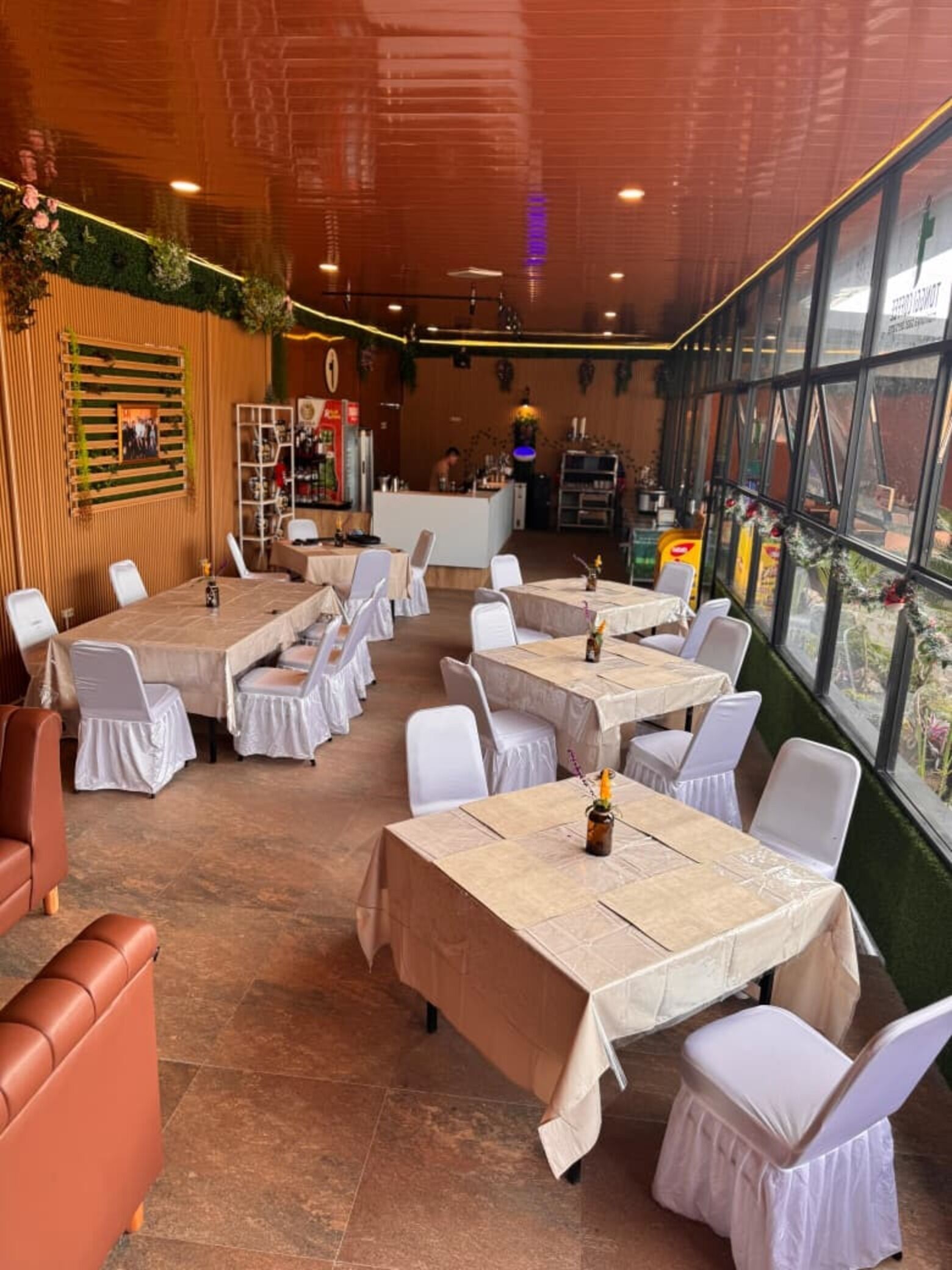 Un restaurante con varias mesas y sillas, una zona de bar y amplios ventanales con vistas.