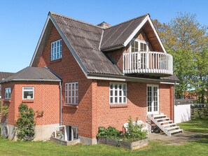 Enjoy the charming balcony with a garden view from this two-story house.