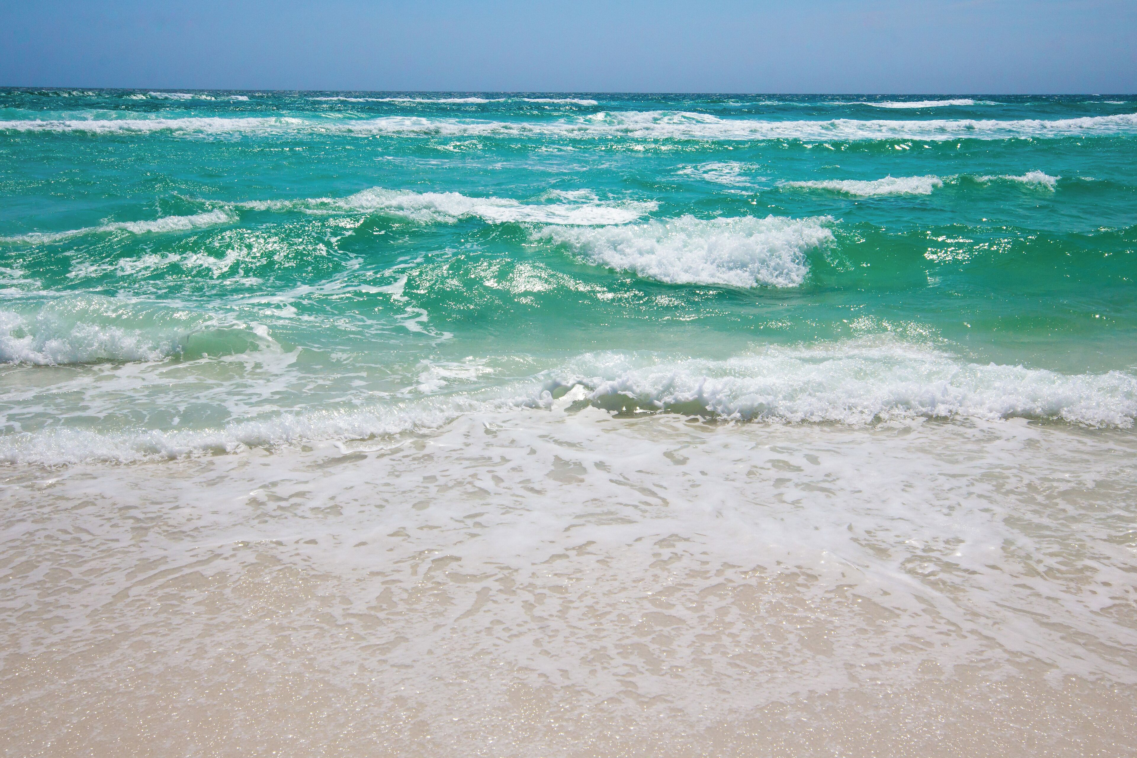 Une plage avec des vagues et une eau cristalline.