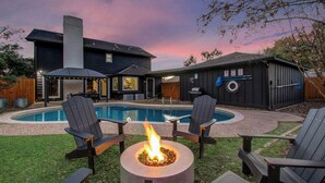 Un jardin avec une piscine, deux fauteuils Adirondack, un foyer et un barbecue.