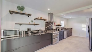 Une cuisine moderne dotée d’un îlot central, d’appareils électroménagers intégrés et d’étagères décoratives.