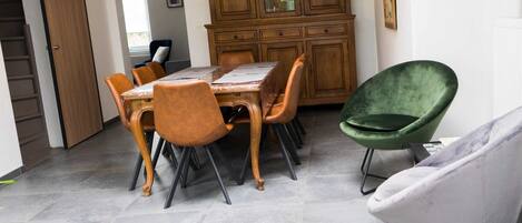 A dining area with a wooden table and chairs, a green chair, and a white chair.