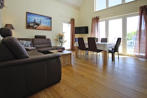 A modern living room with a sofa, dining table, chairs, a TV, and a painting on the wall. - Appartement Hafenflair am Plauer See (Plau am See)