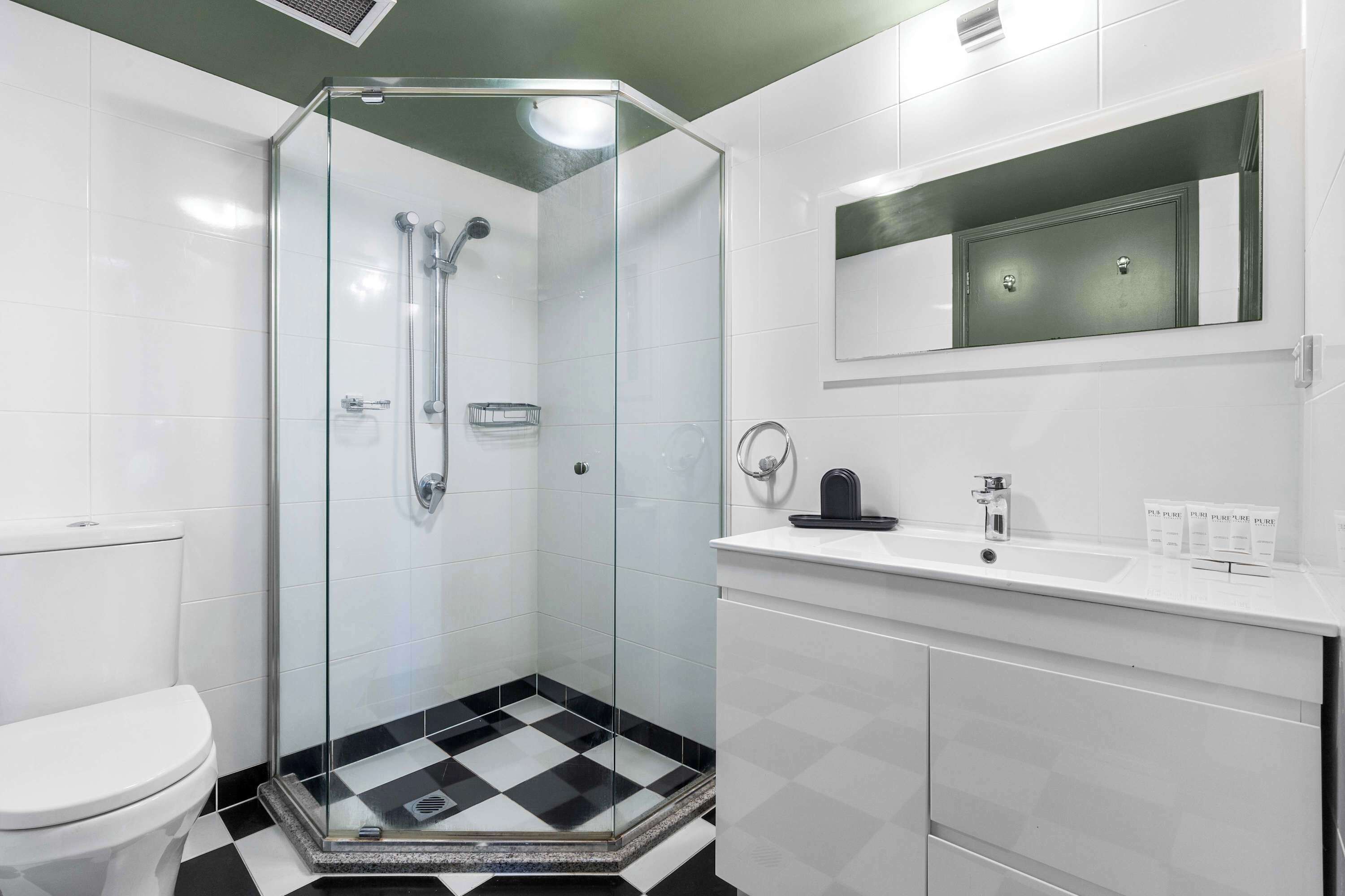 A modern bathroom with a glass-enclosed shower, a white sink, and a mirror above the sink.