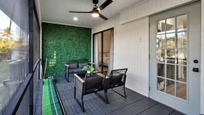 Un balcon doté d’un ventilateur de plafond, d’un mur végétal, d’un canapé et d’une table avec des chaises.