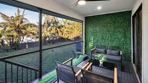 Une terrasse extérieure moderne, dotée d’un espace repas, d’un ventilateur de plafond et d’un mur végétal.