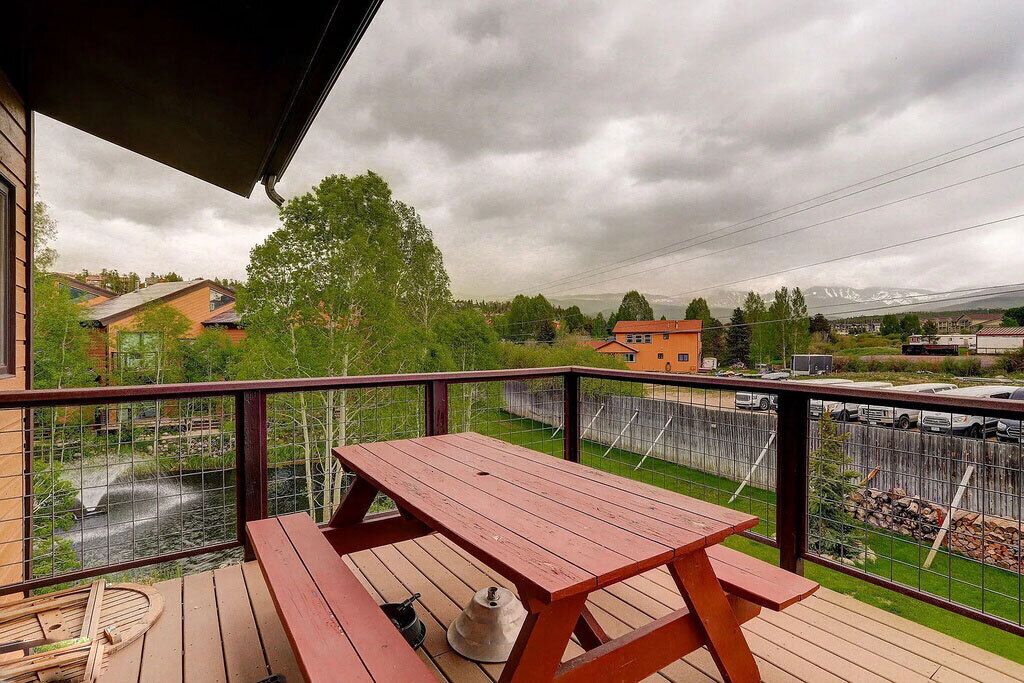 A wooden deck with a picnic table, a small table with a hat, and a chair.