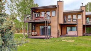 A modern two-story house with a balcony, large windows, and a well-maintained lawn.