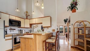 A spacious kitchen with wooden cabinetry, a central island with bar stools, and a dining area with a wooden table and chairs.