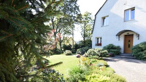 Una casa con un giardino curato, un vialetto lastricato e un ingresso con un piccolo portico.