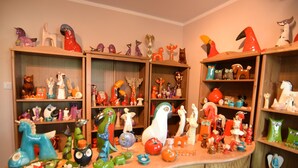 Una stanza con scaffali in legno che espongono diverse figurine di animali in ceramica colorata.