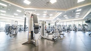 A spacious gym with various exercise machines, large windows, and a high ceiling with recessed lighting. - Lely, Naples home with The Players Club at Lely Resort Amenities (Naples)