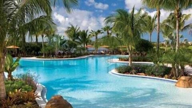 A swimming pool surrounded by palm trees and greenery. - Lely, Naples home with The Players Club at Lely Resort Amenities (Naples)