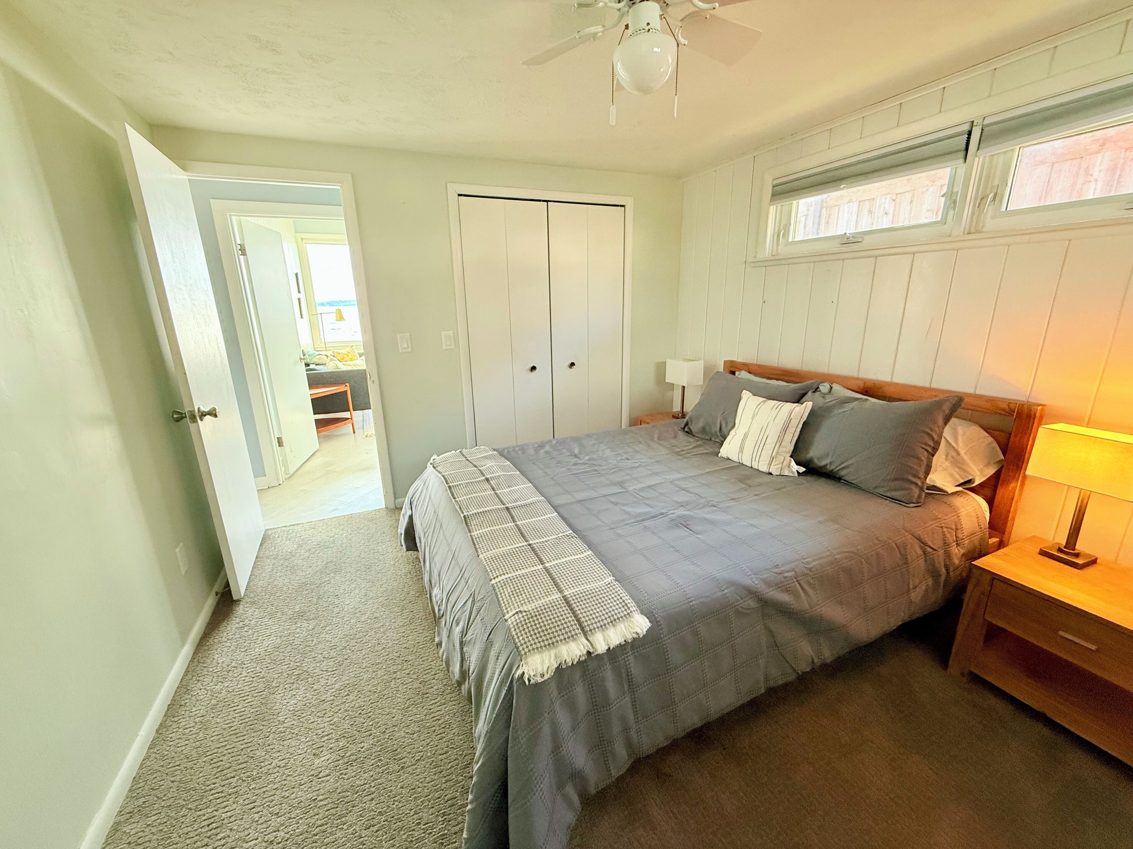 A bedroom with a bed, nightstands, a ceiling fan, and a wardrobe.
