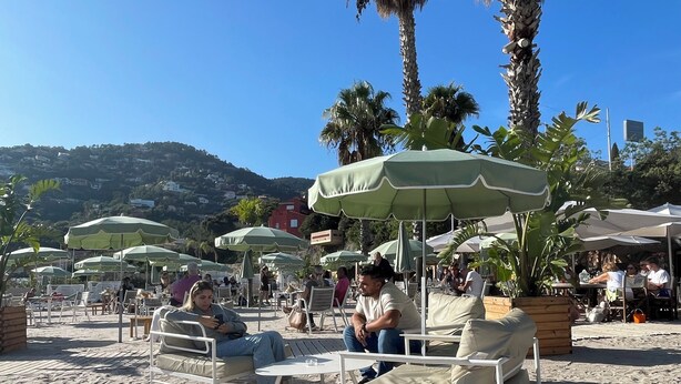 Outdoor seating with umbrellas, a sandy beach, and palm trees. - Enchanting beach house in Théoule-sur-Mer directly on the Plage de la Figueirette (Théoule-sur-Mer)